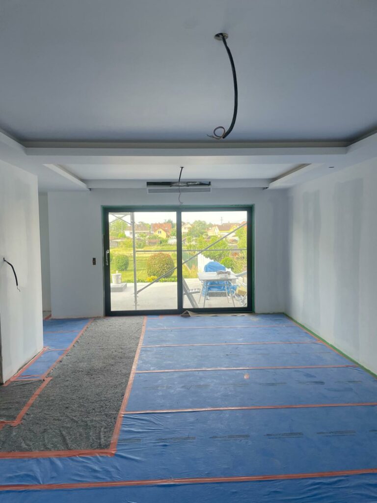 Salle en rénovation avec un faux plafond en préparation et des protections au sol.