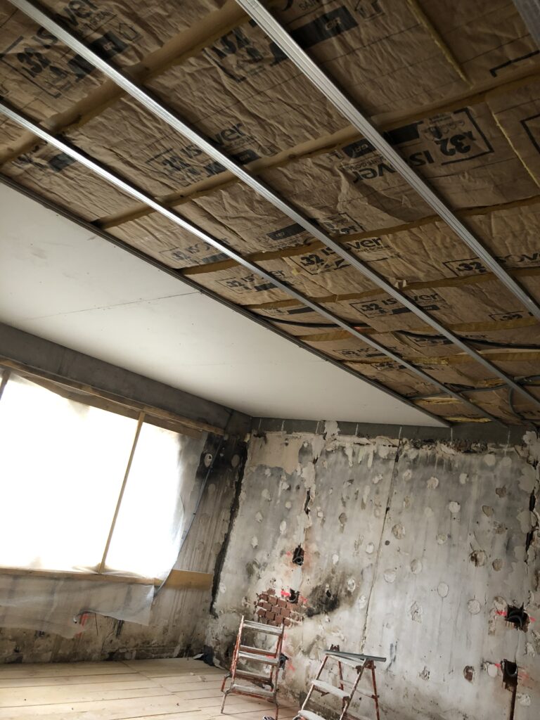 Travaux d'isolation en cours avec des panneaux isolants posés sous une ossature métallique dans un espace en rénovation.