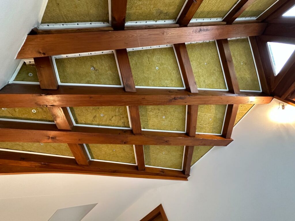 Charpente apparente avec isolation intégrée, mettant en valeur une finition en bois et des matériaux isolants.