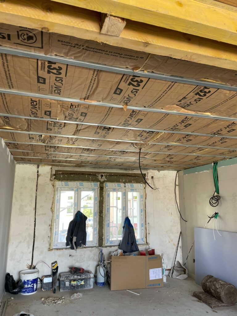 Installation d'isolation en cours avec des panneaux isolants et une ossature métallique dans une pièce en rénovation.