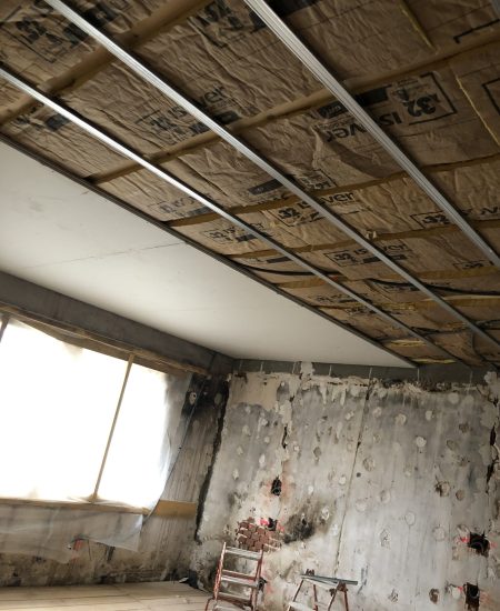Travaux d'isolation en cours avec des panneaux isolants posés sous une ossature métallique dans un espace en rénovation.