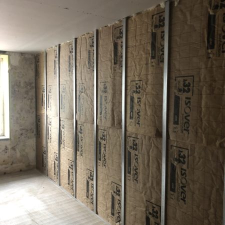 Cloison intérieure avec isolation acoustique en cours de réalisation, présentant une structure métallique et des panneaux isolants.