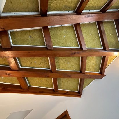 Charpente apparente avec isolation intégrée, mettant en valeur une finition en bois et des matériaux isolants.