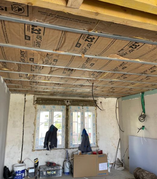 Installation d'isolation en cours avec des panneaux isolants et une ossature métallique dans une pièce en rénovation.