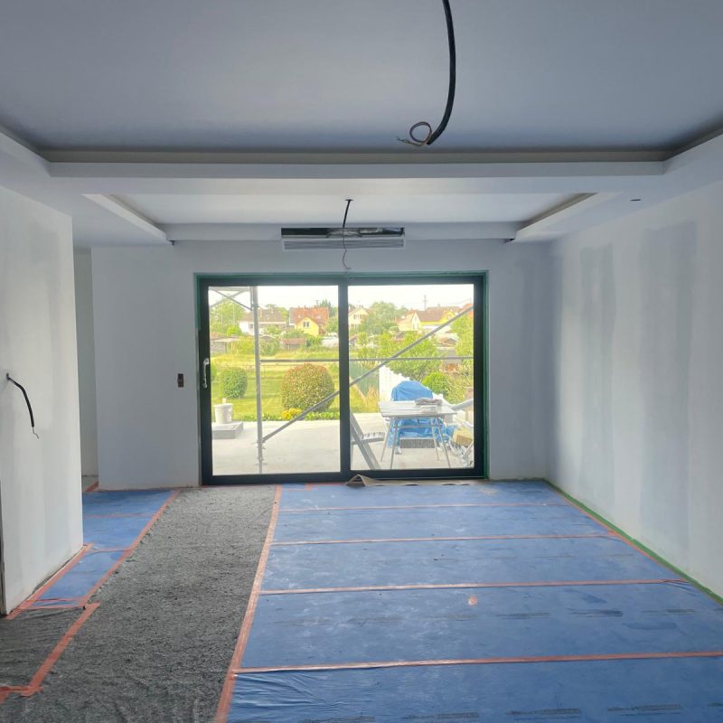 Salle en rénovation avec un faux plafond en préparation et des protections au sol.